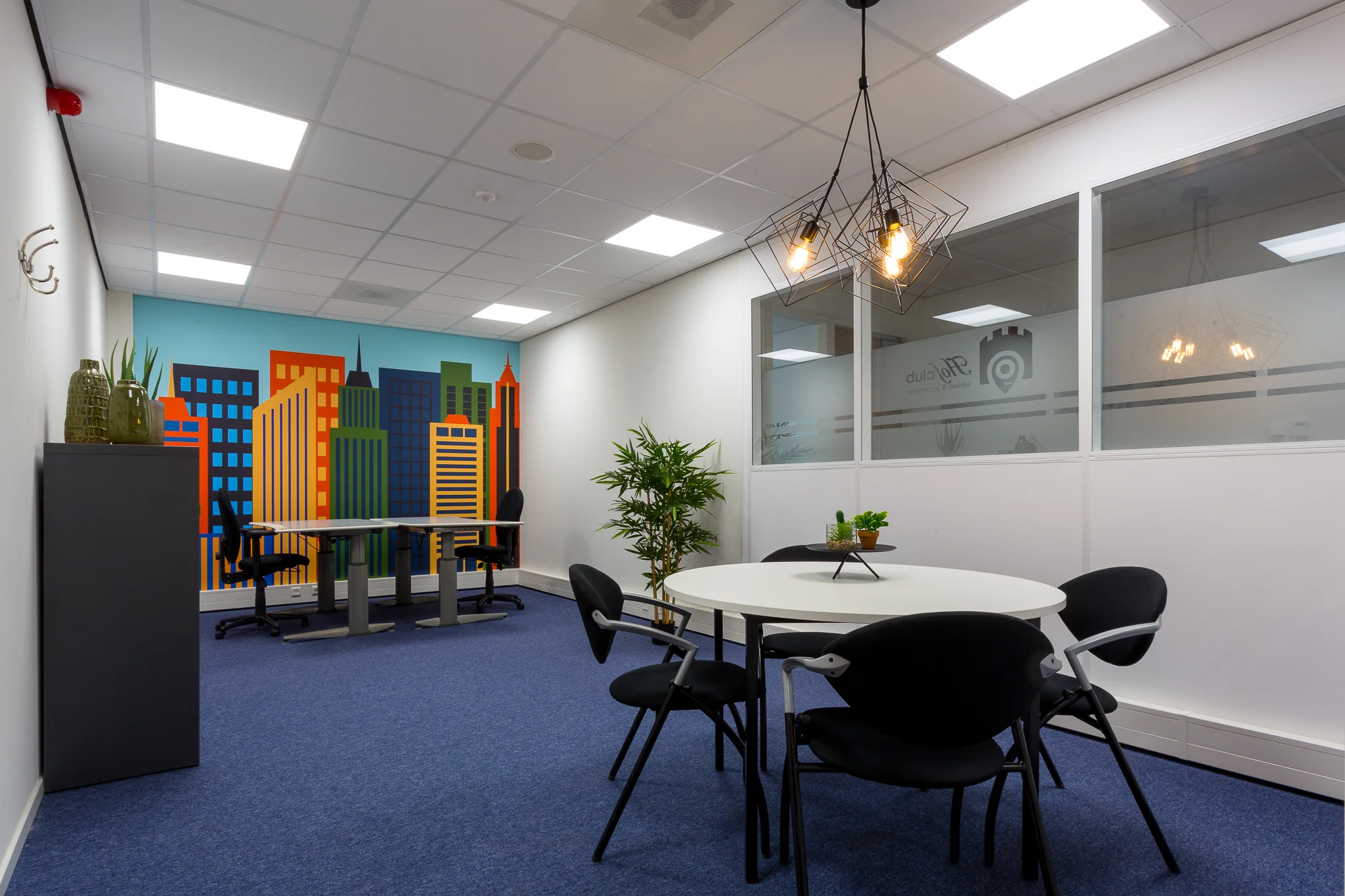 Moderne kantoorruimte aan de Niels Bohrweg met een kleurrijke muurschildering van een skyline, ronde vergadertafel en bureaus.